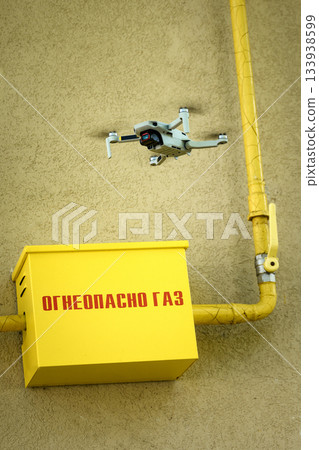 Drone in the air inspecting gas box and pipe, and text Flammable Gas on wall dangerous closeup background Drone in the air inspecting gas box and pipe, and text Flammable Gas on wall dangerous closeup background 133938599