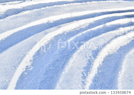 Tractor several parallel tracks in snow blue tone sunny day Tractor several parallel tracks in snow blue tone sunny day 133938674