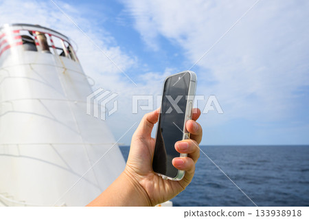 Hand holding a smartphone on a ship 133938918