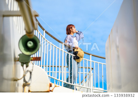 A woman on a boat looks up at the blue sky 133938932