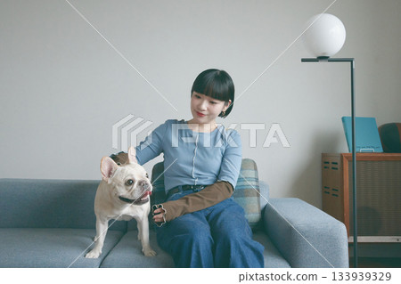 一位年輕女子和一隻狗在沙發上放鬆休息。 133939329