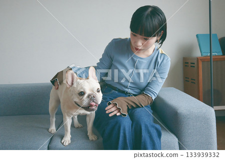 A young woman and a dog relaxing on the sofa A young woman and a dog relaxing on the sofa 133939332