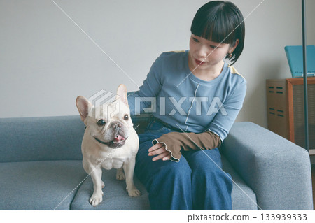 一位年輕女子和一隻狗在沙發上放鬆休息。 133939333