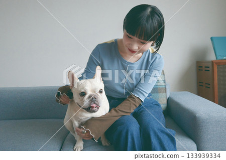 一位年輕女子和一隻狗在沙發上放鬆休息。 133939334