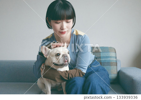 一位年輕女子和一隻狗在沙發上放鬆休息。 133939336