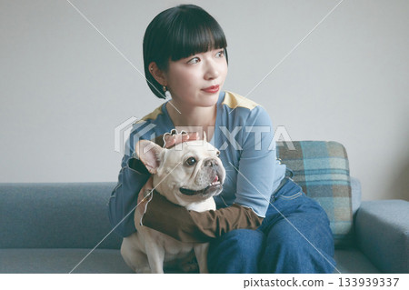 一位年輕女子和一隻狗在沙發上放鬆休息。 133939337