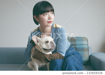 一位年輕女子和一隻狗在沙發上放鬆休息。 133939338