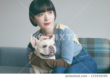 一位年輕女子和一隻狗在沙發上放鬆休息。 一位年輕女子和一隻狗在沙發上放鬆休息。 133939399