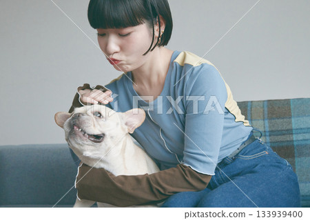 一位年輕女子和一隻狗在沙發上放鬆休息。 133939400