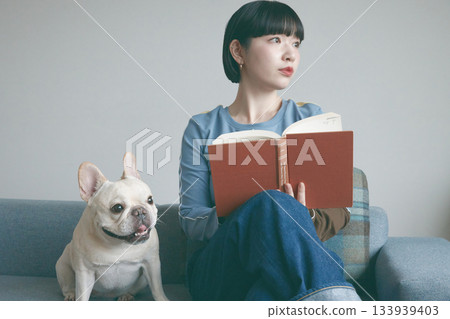 女人和狗在沙發上看書 133939403