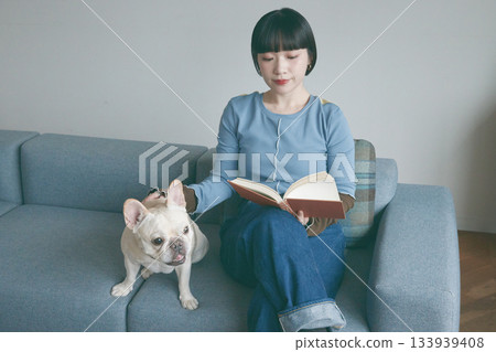 女人和狗在沙發上看書 133939408