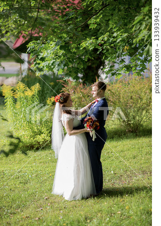 Bride and groom embracing under leafy tree canopy on wedding day 133939432