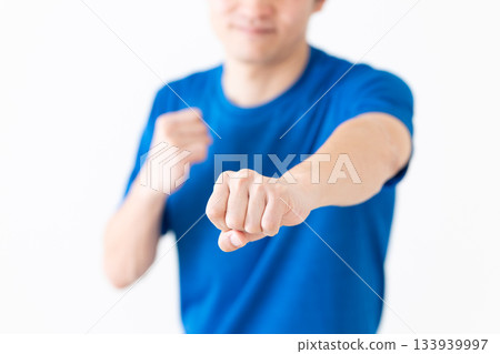 A middle-aged man in a T-shirt taking a martial arts stance 133939997