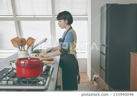 一個女人在做飯,一隻狗在一旁看著。 一個女人在做飯,一隻狗在一旁看著。 133940046