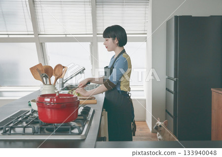 A woman cooking and a dog watching over her A woman cooking and a dog watching over her 133940048