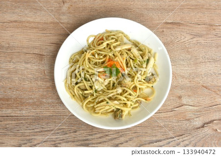 spicy stir fried spaghetti with scallop in garlic butter sauce topping shrimp egg on plate  133940472