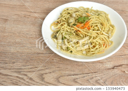 spicy stir fried spaghetti with scallop in garlic butter sauce topping shrimp egg on plate  133940473