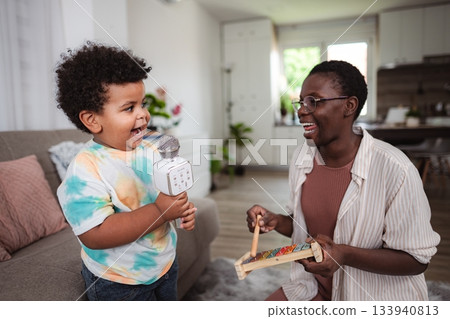 Mother and son singing karaoke, playing musical instruments at home Mother and son singing karaoke, playing musical instruments at home 133940813