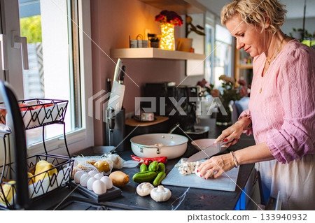 Woman chopping fresh mushrooms for healthy meal preparation 133940932