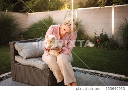 Woman petting cat in garden relaxing outdoors 133940933
