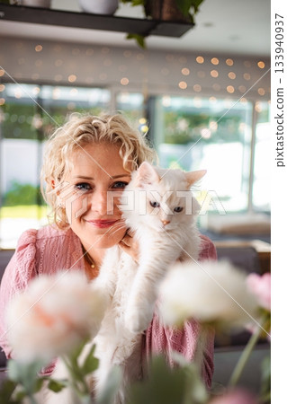 Woman smiling and holding her fluffy white cat 133940937
