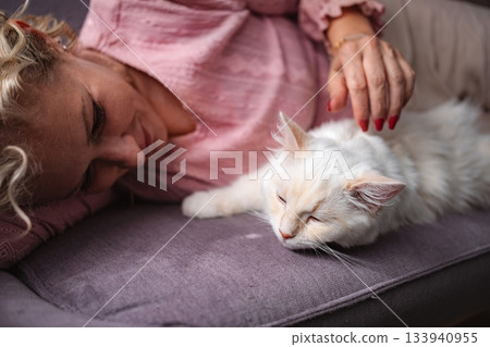 Woman relaxing with cat on sofa feeling affection 133940955
