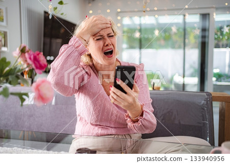 Woman reacting to bad news on smartphone with shock Woman reacting to bad news on smartphone with shock 133940956