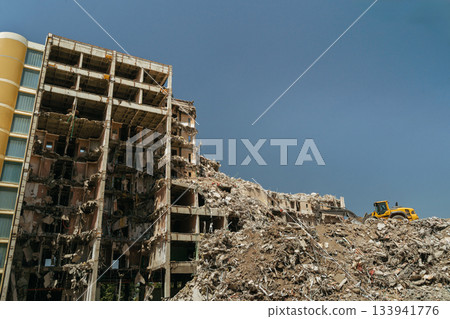 A destroyed apartment building ruins under active demolition 133941776