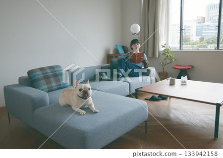 一位年輕女子和一隻狗在沙發上放鬆休息。 133942158