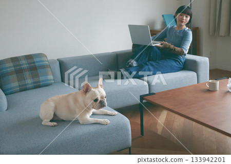 一位年輕女子和一隻狗在沙發上放鬆休息。 133942201