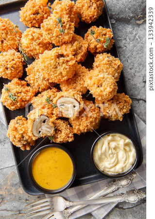Crispy deep-fried mushrooms in panko breading close-up in a plate. Vertical top view Crispy deep-fried mushrooms in panko breading close-up in a plate. Vertical top view 133942339