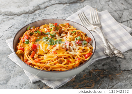 One pot Taco Pasta with ground beef, green chili, onion, cheese, tomatoes, spices close-up in a plate on the table. Horizontal closeup on the plate. Horizontal 133942352