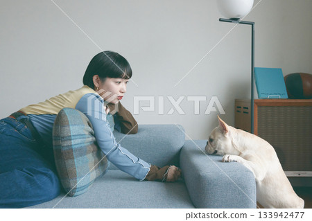 Woman and dog relaxing on sofa 133942477