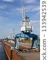 Magdeburg industrial port harbor canal scene. Crane recycling facility loading large scrap metal pile canal barge background. Industrial area scene waste management resource reuse concept 133942539