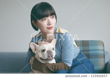 一位年輕女子和一隻狗在沙發上放鬆休息。 133942657