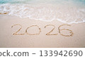 number 2026  write on sandy beach for new year, with ripple sea wave crashing with white bubble, 2026 New Year celebration concept 133942690