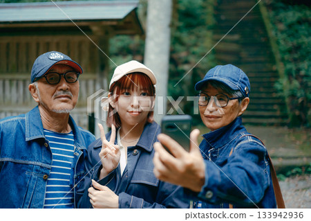 Family trip scene with three parents and children taking a selfie with a smartphone in front of the shrine's torii gate Family trip scene with three parents and children taking a selfie with a smartphone in front of the shrine's torii gate 133942936