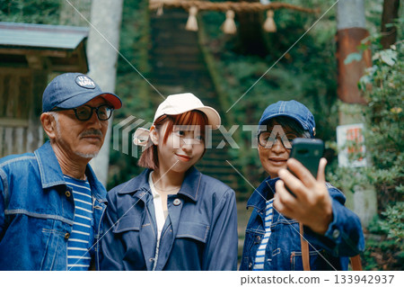 一家三口在神社鳥居前用智慧型手機自拍，畫面溫馨感人。 133942937