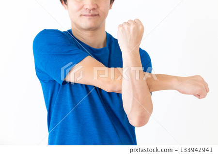 A middle-aged man in a T-shirt doing arm stretching exercises A middle-aged man in a T-shirt doing arm stretching exercises 133942941
