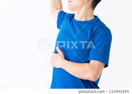 A middle-aged man in a T-shirt doing waist stretching exercises 133942945