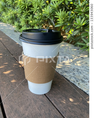 Morning coffee cup on wooden bench with sunlight 133943060