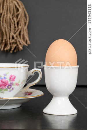 egg in its egg cup next to a pretty cup of coffee 133943118