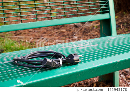 outdoor. An electrical cable coiled on a public bench 133943178