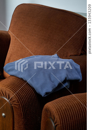 Clothing draped over the armrest of a velvet armchair Clothing draped over the armrest of a velvet armchair 133943209