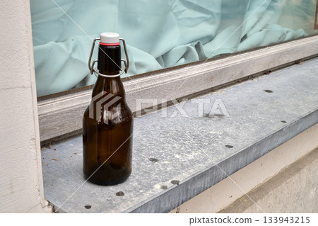 Outdoor. Empty beer bottle on a windowsill Outdoor. Empty beer bottle on a windowsill 133943215