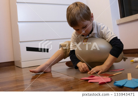 Child playing on floor decorating craft balloon Child playing on floor decorating craft balloon 133943471