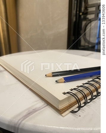 sketchbook with pencils on white marble table 133943606