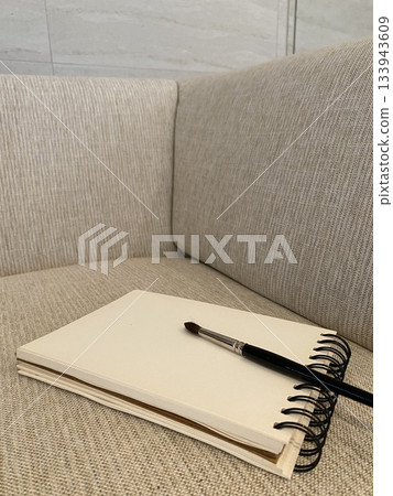 sketchbook with black paintbrush on modern sofa 133943609