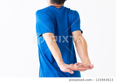 A middle-aged man in a T-shirt doing arm stretching exercises 133943613