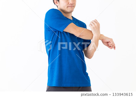 A middle-aged man in a T-shirt doing arm stretching exercises A middle-aged man in a T-shirt doing arm stretching exercises 133943615